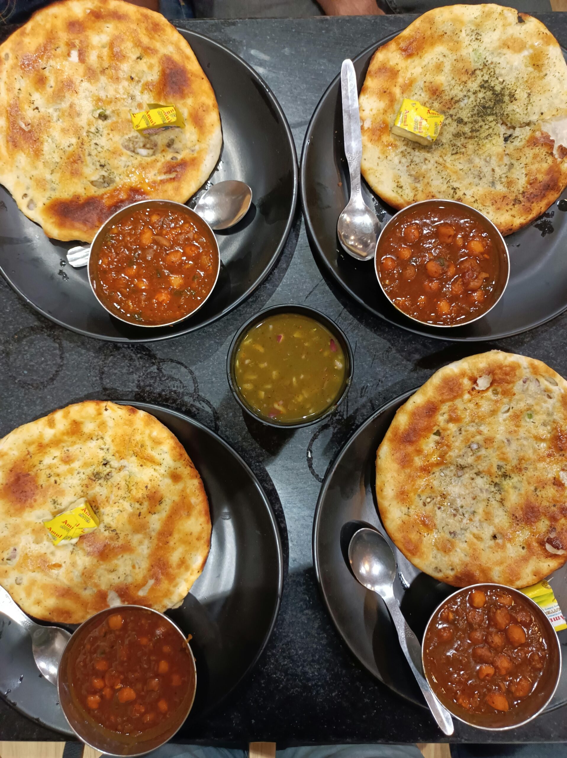 Delicious chole bhature meal served on black plates at an Indian restaurant.